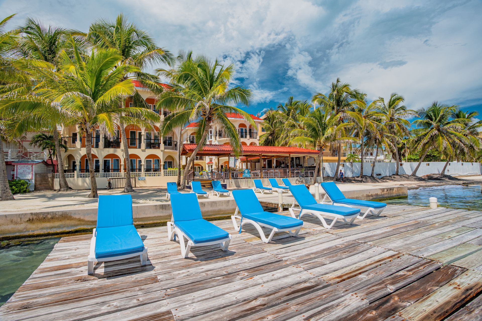A row of blue lounge chairs are sitting on a wooden dock.