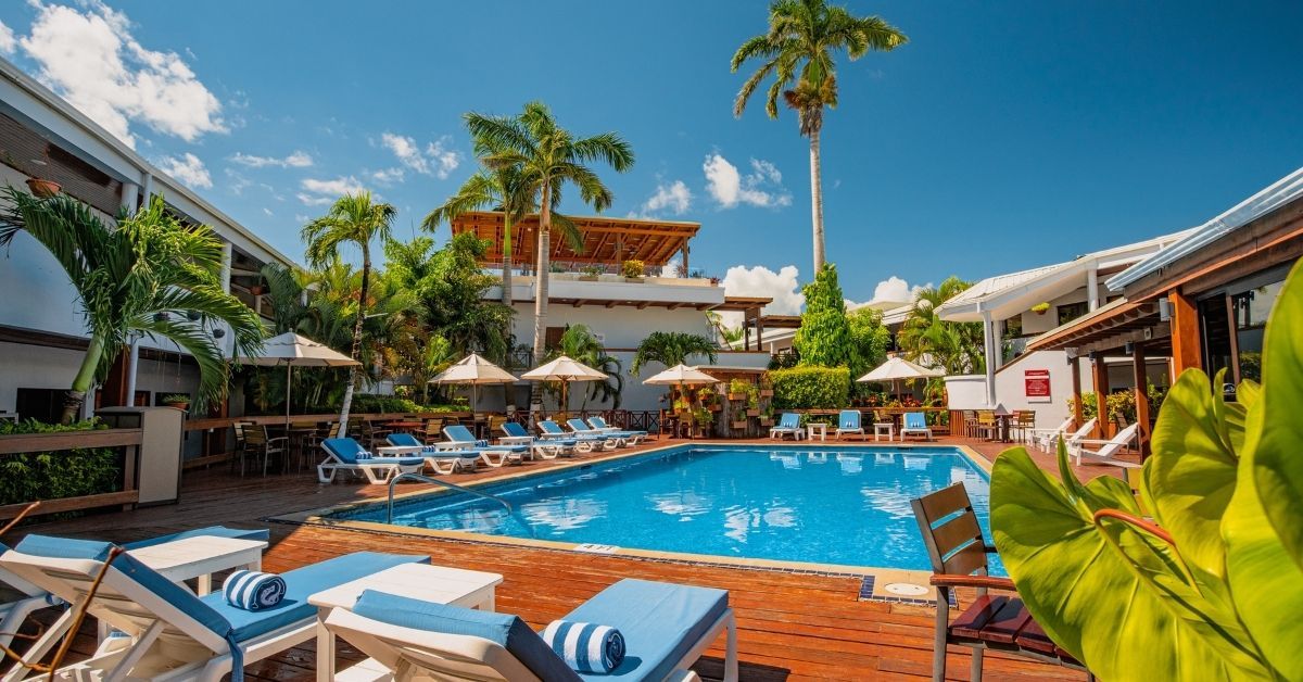 A large swimming pool surrounded by chairs and palm trees in a resort.
