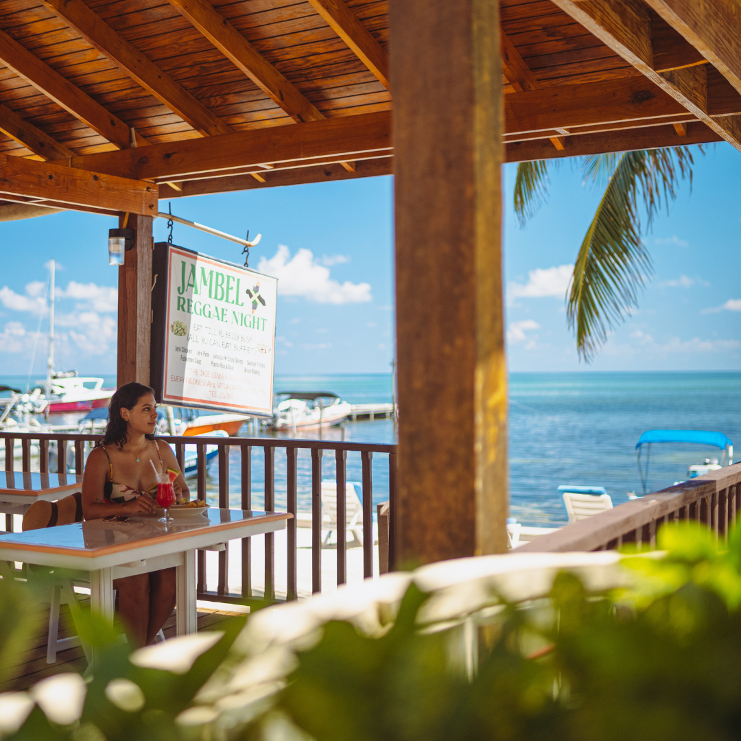 a woman sits at a table with a drink in front of the ocean