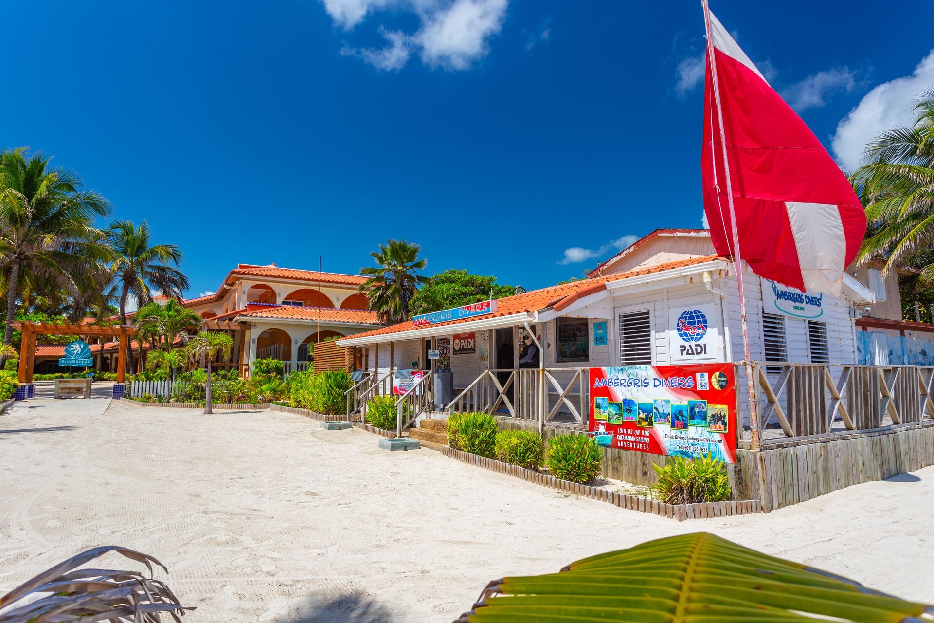 a red and white flag is flying in front of a building on a beach .