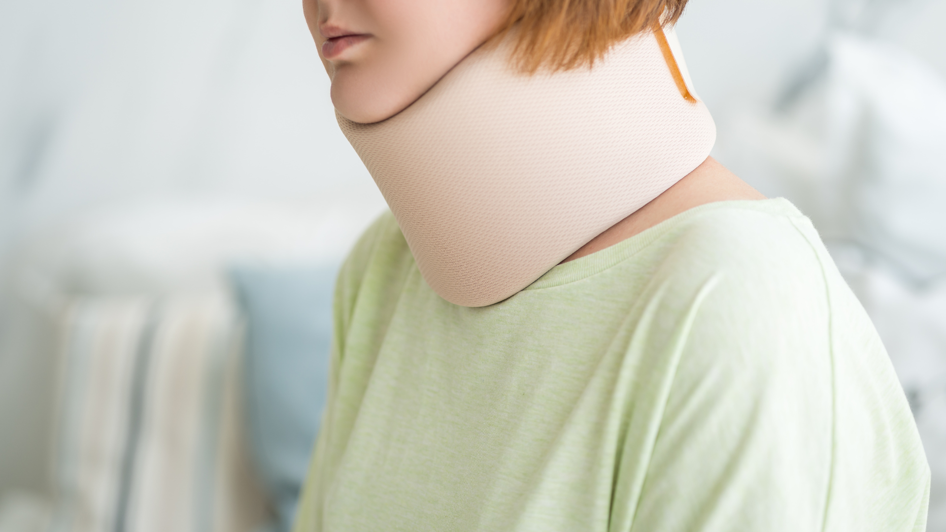 A person in a light green shirt wearing a beige foam cervical neck collar.