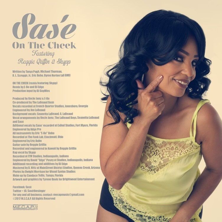 Woman in yellow top, dark hair, finger on cheek, smiling, album cover. Text includes