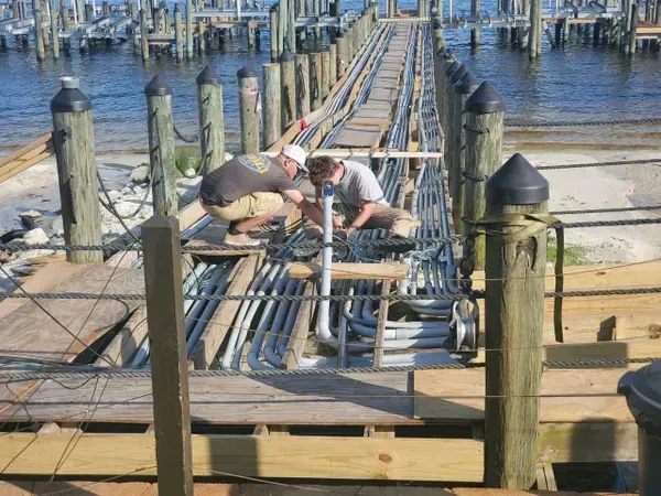 Two men are working on a dock near the water