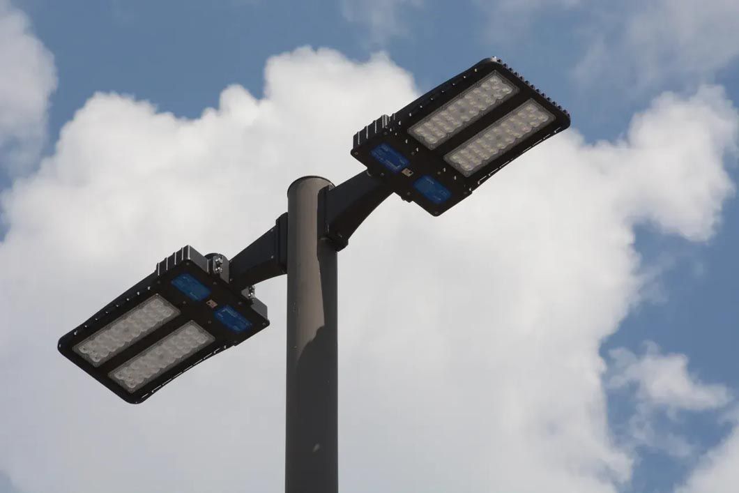 Two street lights on a pole against a cloudy sky