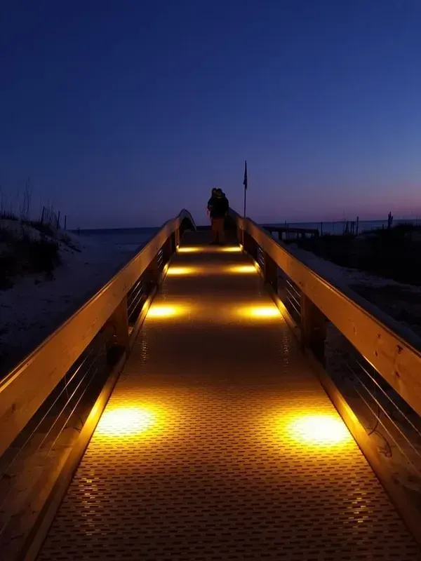 A person is standing on a pier at night