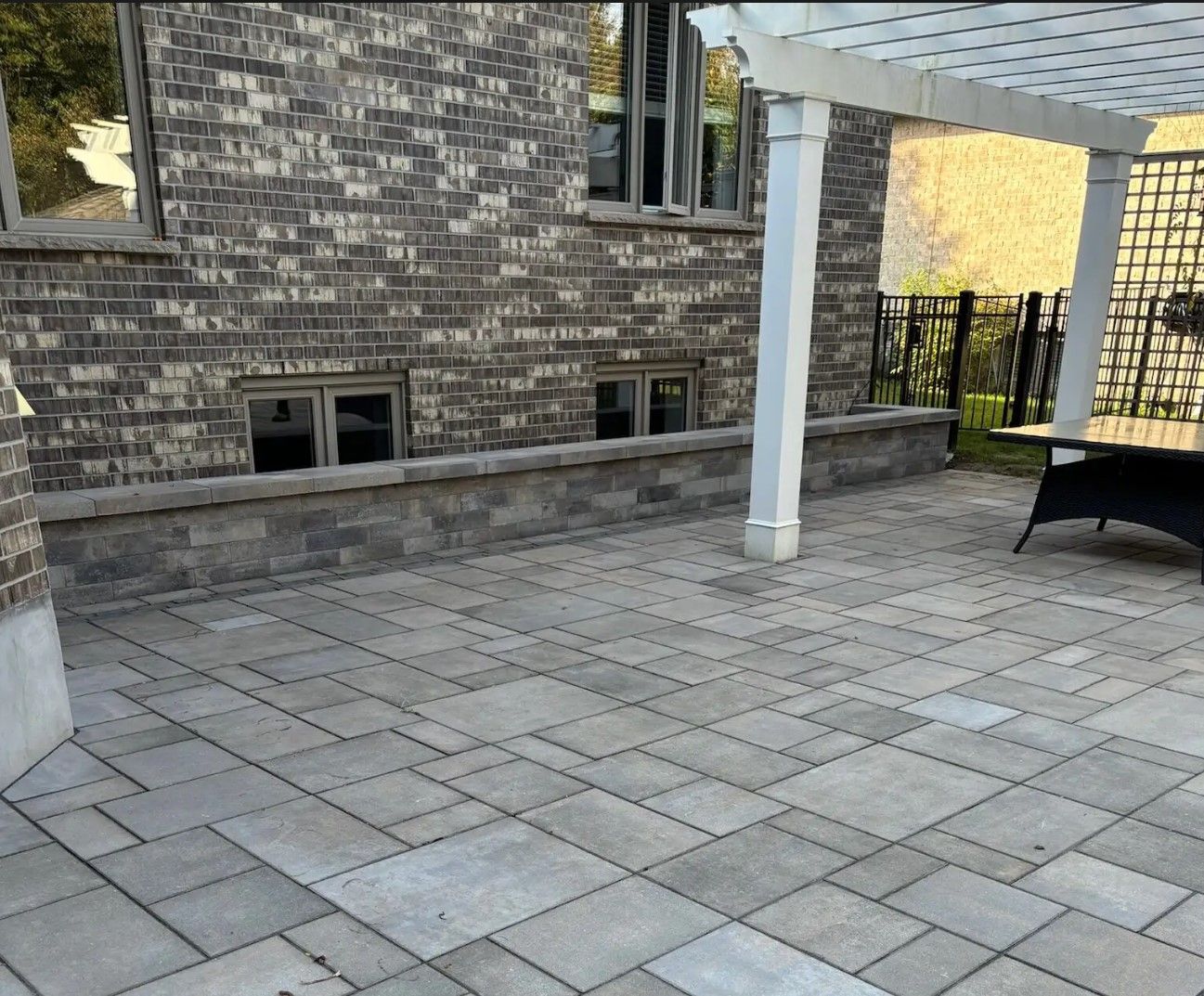 A patio with a pergola and a chair in front of a brick building