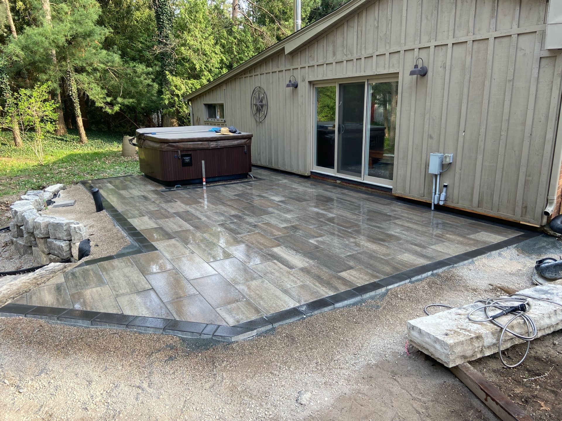 A hot tub is sitting on a patio in front of a house.