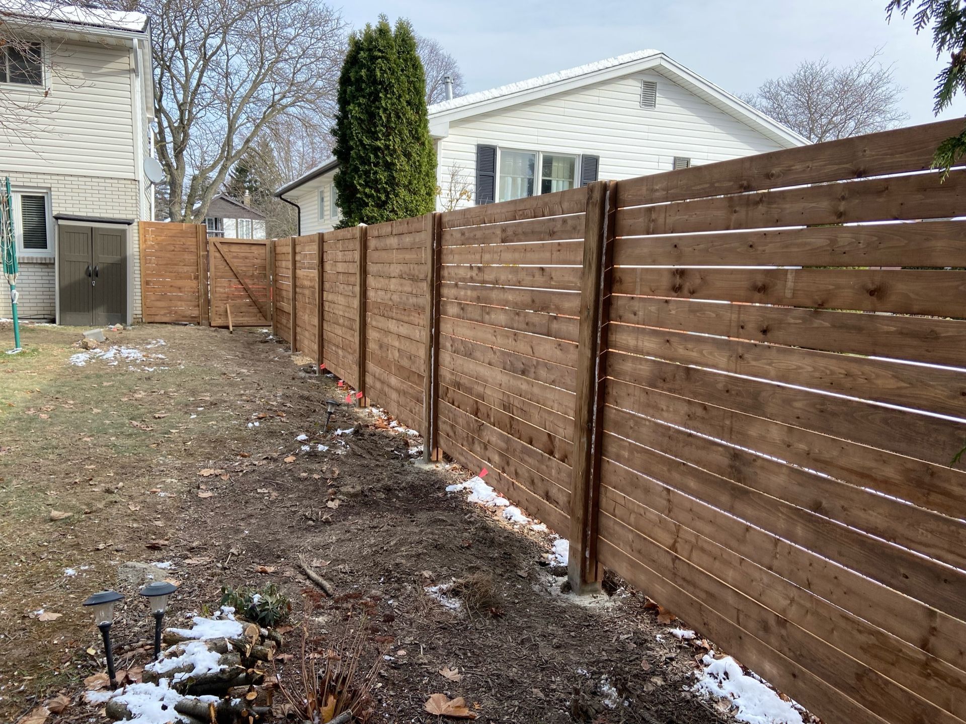 A wooden fence is in the backyard of a house.