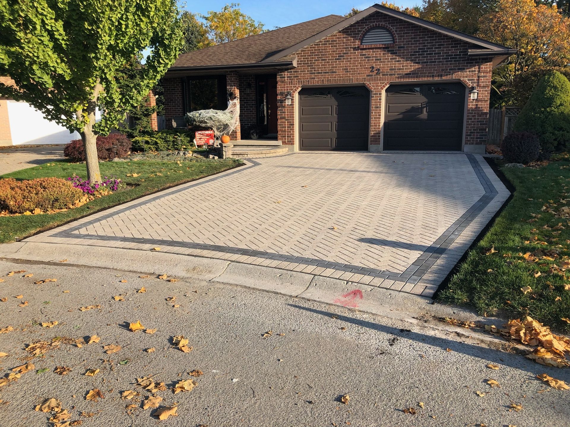 A brick house with a large driveway in front of it.