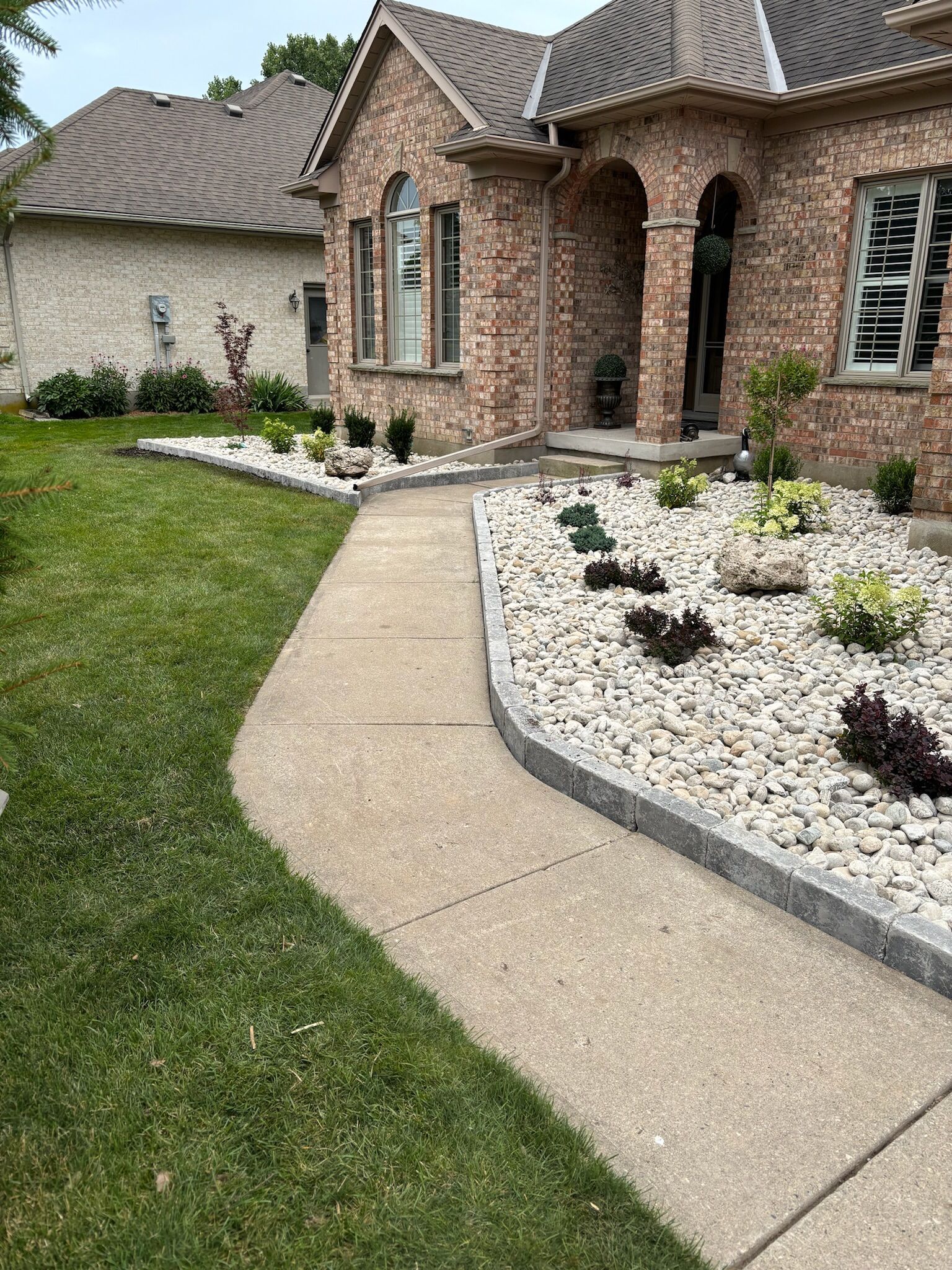 A brick house with a walkway leading to it and a gravel garden in front of it.
