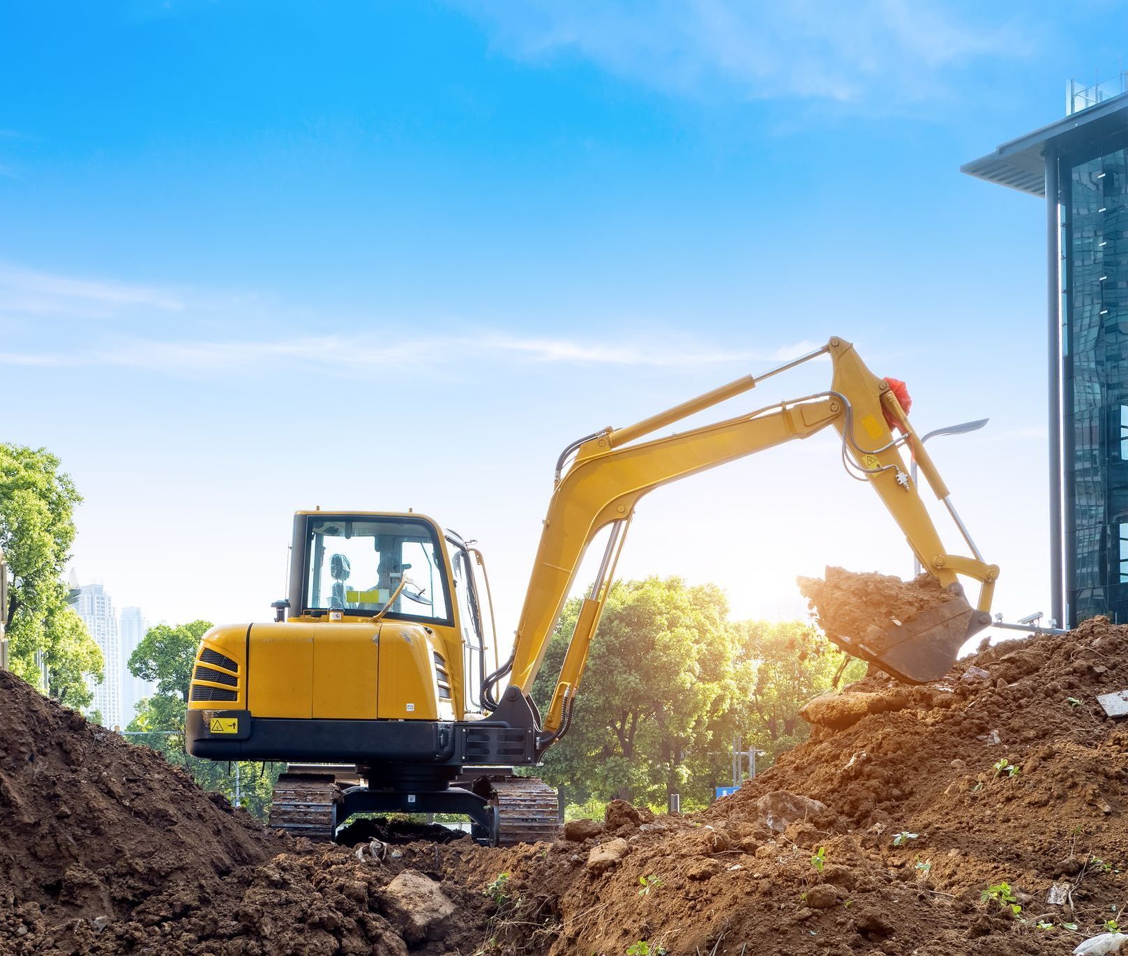 A yellow excavator is digging a hole in the dirt at a construction site.
