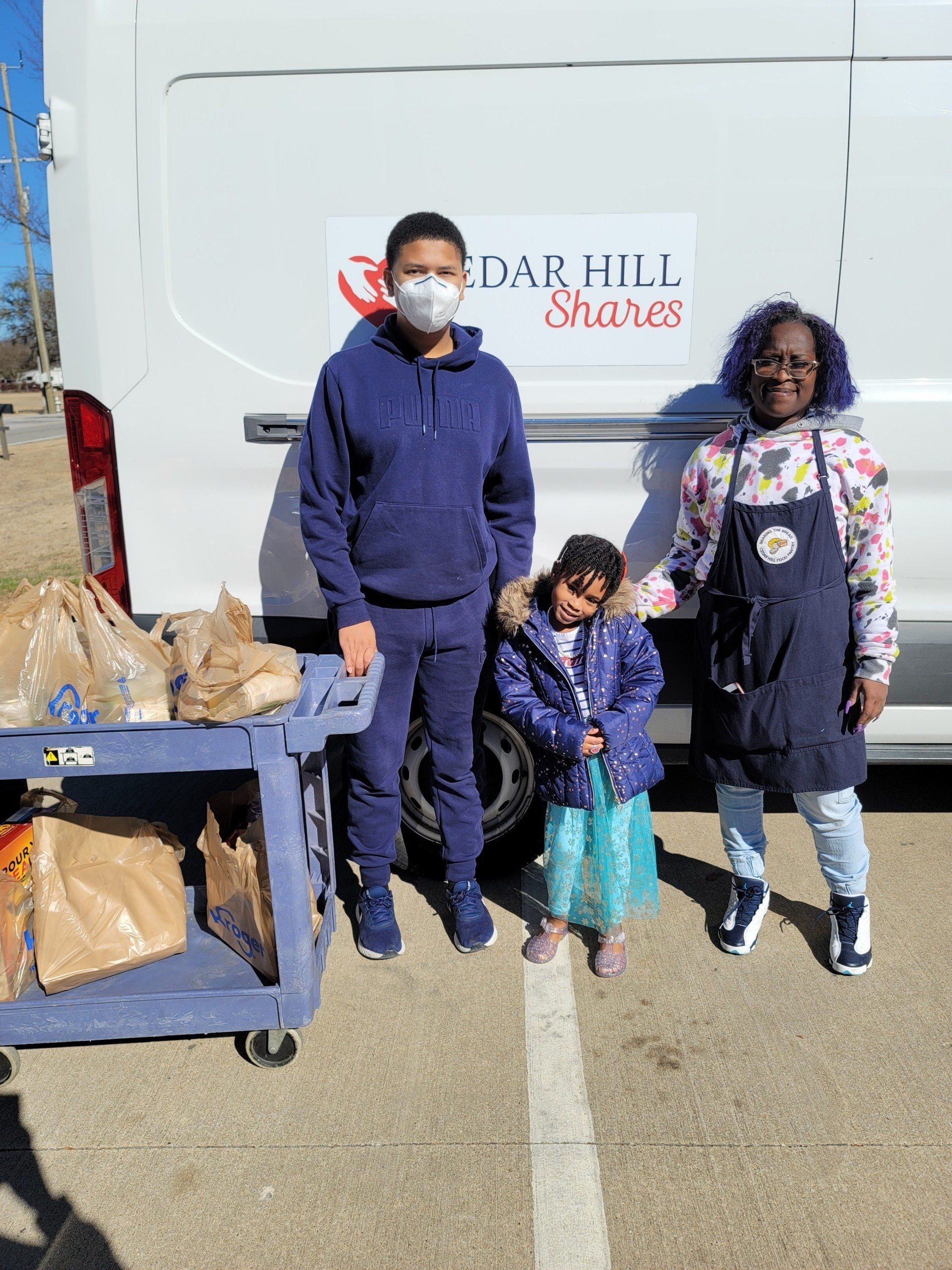 Three people stand by a van labeled 