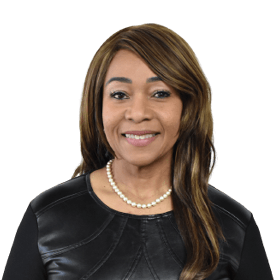 Woman smiling, wearing a black top and pearl necklace, with brown and blonde hair.