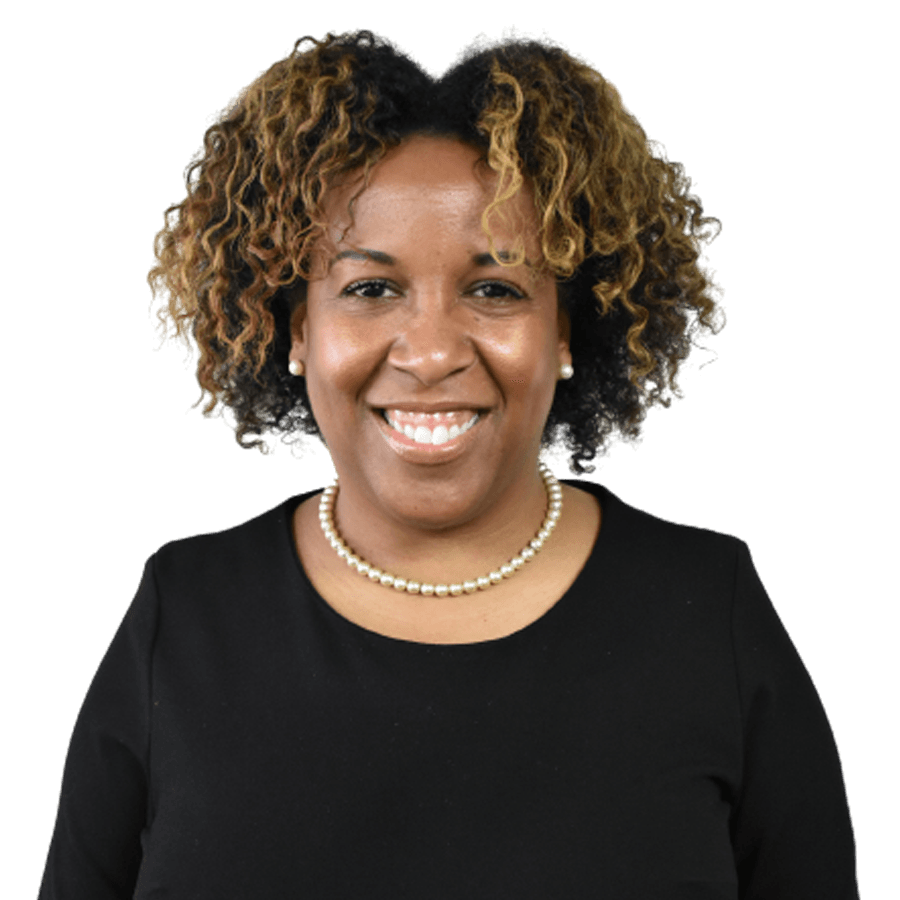 Woman with curly hair smiles, wearing a black top and a pearl necklace.