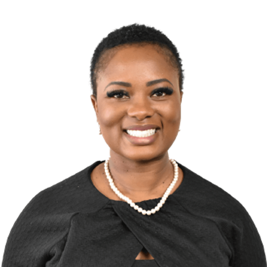 Woman with short hair, wearing a pearl necklace and black top, smiling.