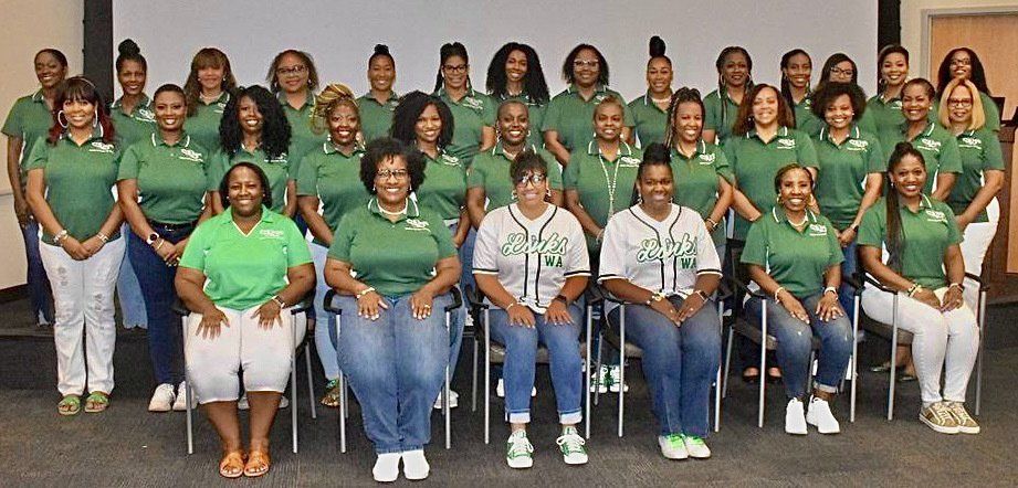 Group of people in green shirts, sitting and standing, posing for a photo.