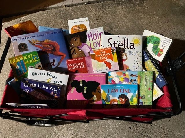 Red wagon overflowing with children's books, including titles like 