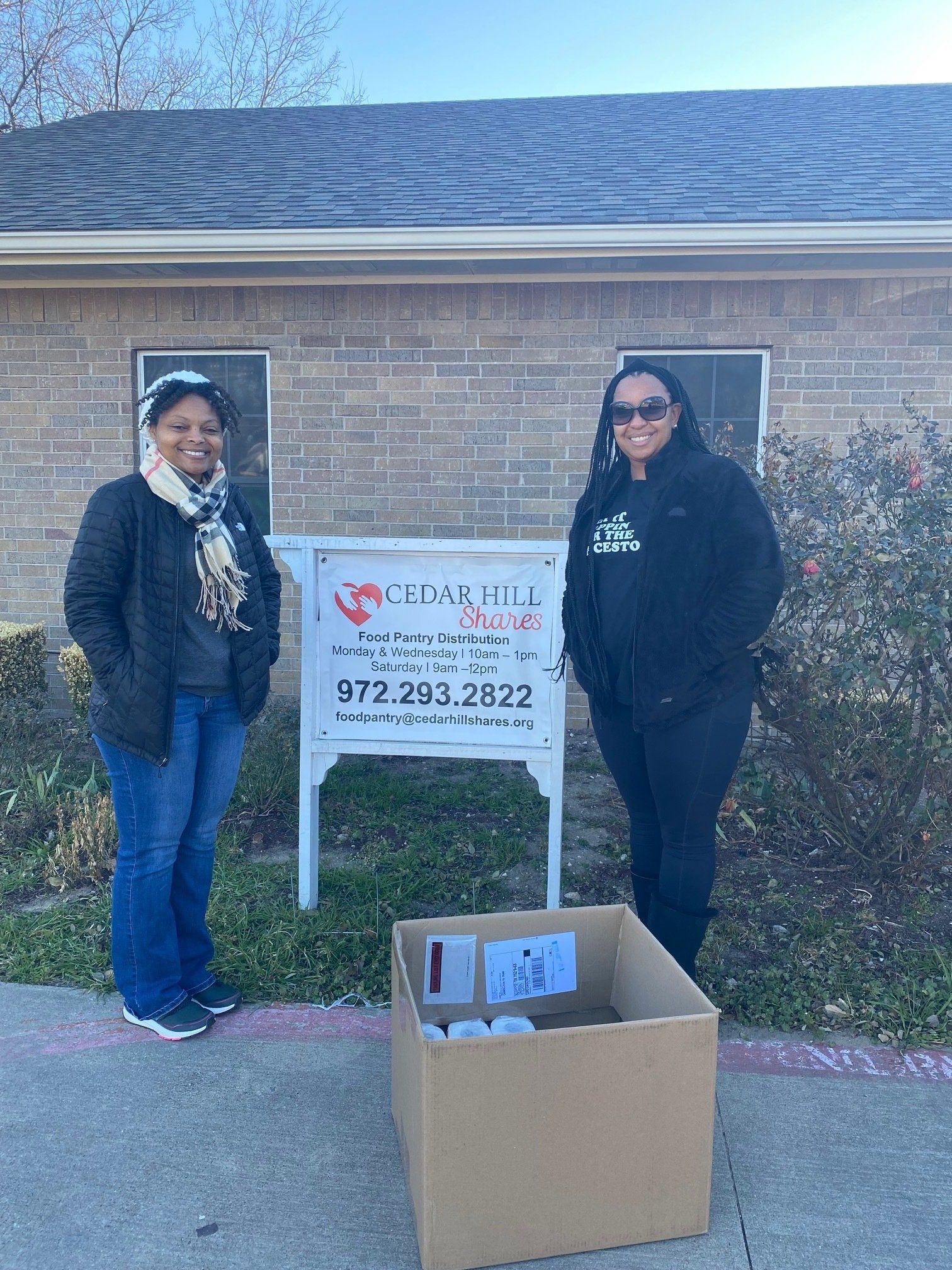 Two women stand near a sign for 