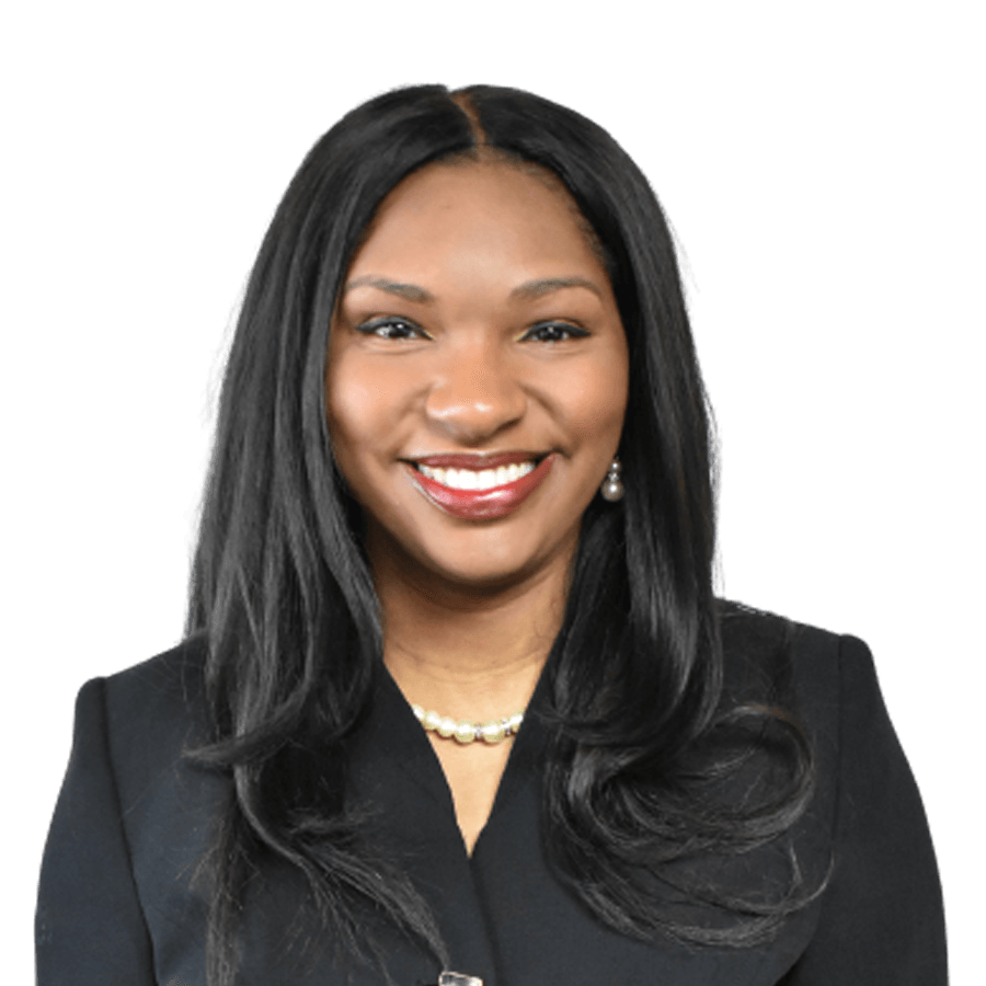 Woman in a black blazer and pearl necklace smiles at the camera against a white background.