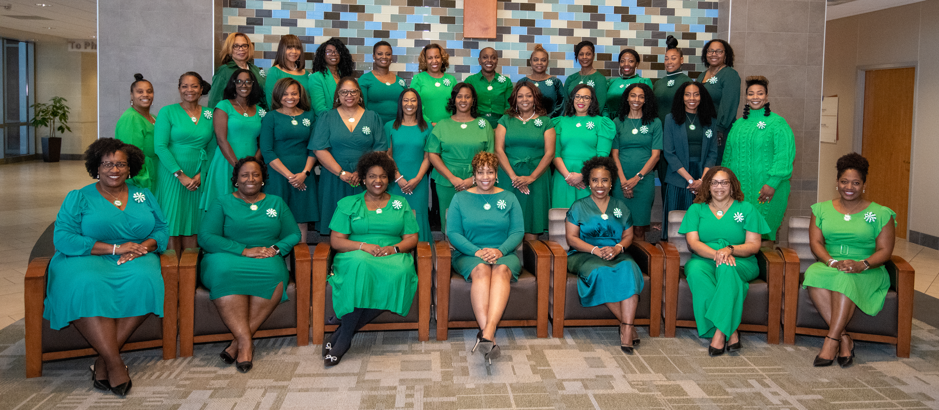 Group of women wearing various shades of green, posing indoors.