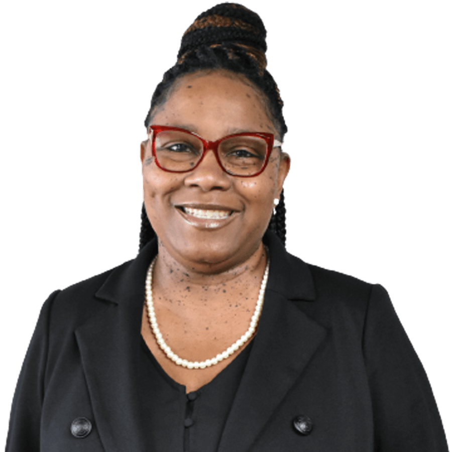 Woman in glasses, smiling, wearing a black blazer and pearl necklace.