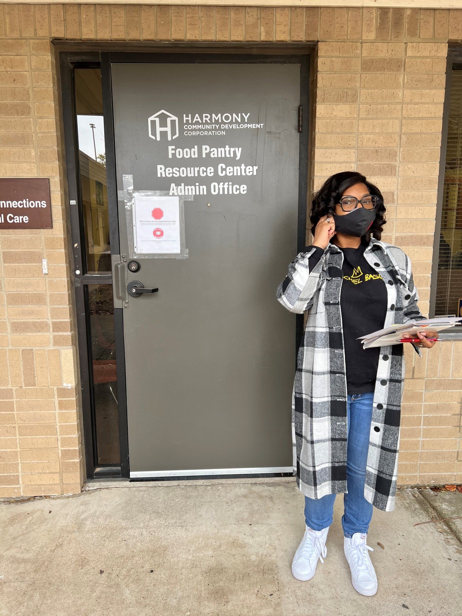 Woman in mask outside a building door labeled 