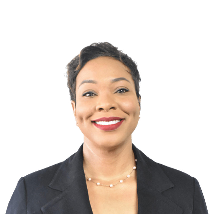 Woman in a black blazer smiles, wearing a pearl necklace, against a white background.