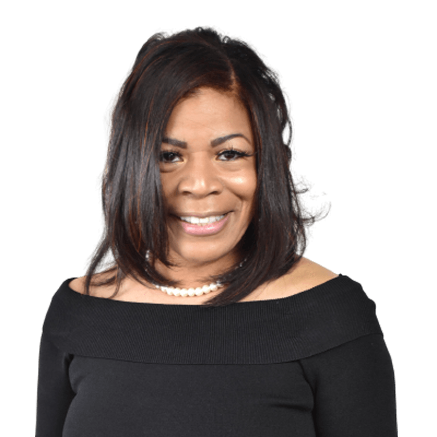 Woman in black off-the-shoulder top, smiling, wearing a pearl necklace, with shoulder-length dark hair.
