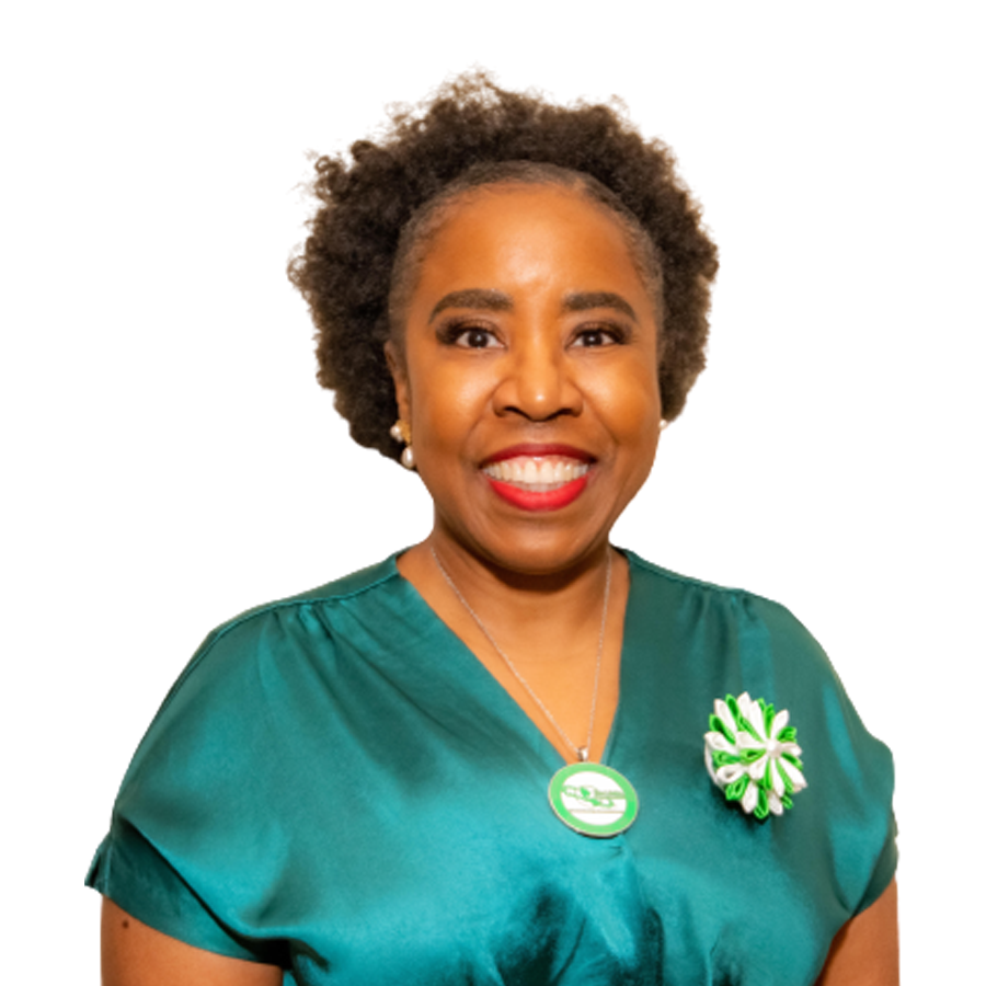 Woman in green top smiles, wearing a pin and a flower-like accessory.