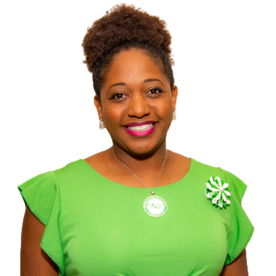 Woman in a green dress smiles at the camera, wearing a necklace and a decorative pin.