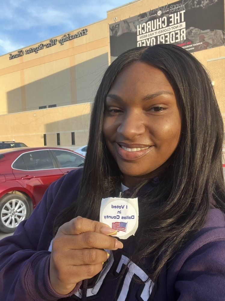 Woman smiles, holding a sticker that says 