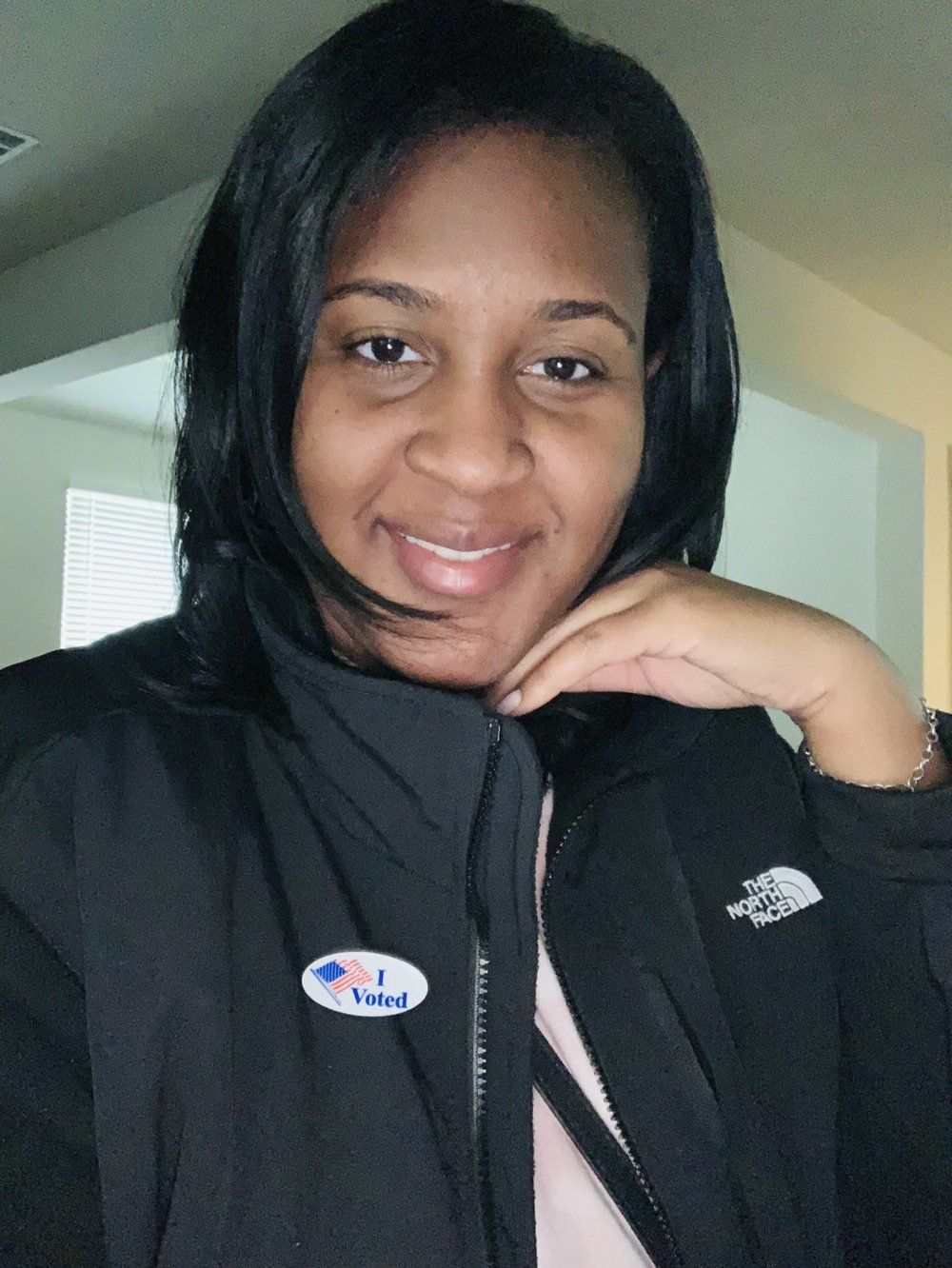 Woman with dark hair, smiling, wearing a jacket with a 