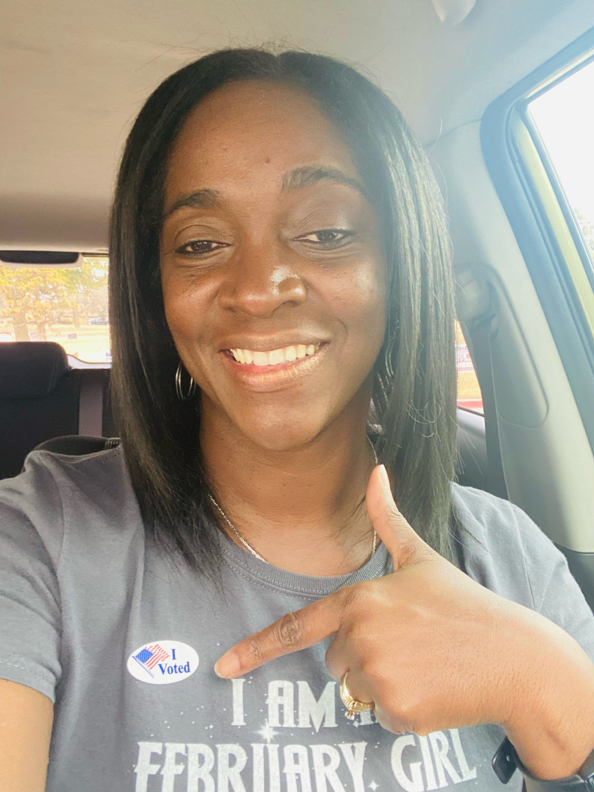 Woman in a car smiles, points at 
