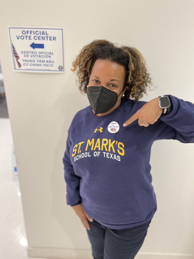 Person in navy sweatshirt at vote center, pointing at 