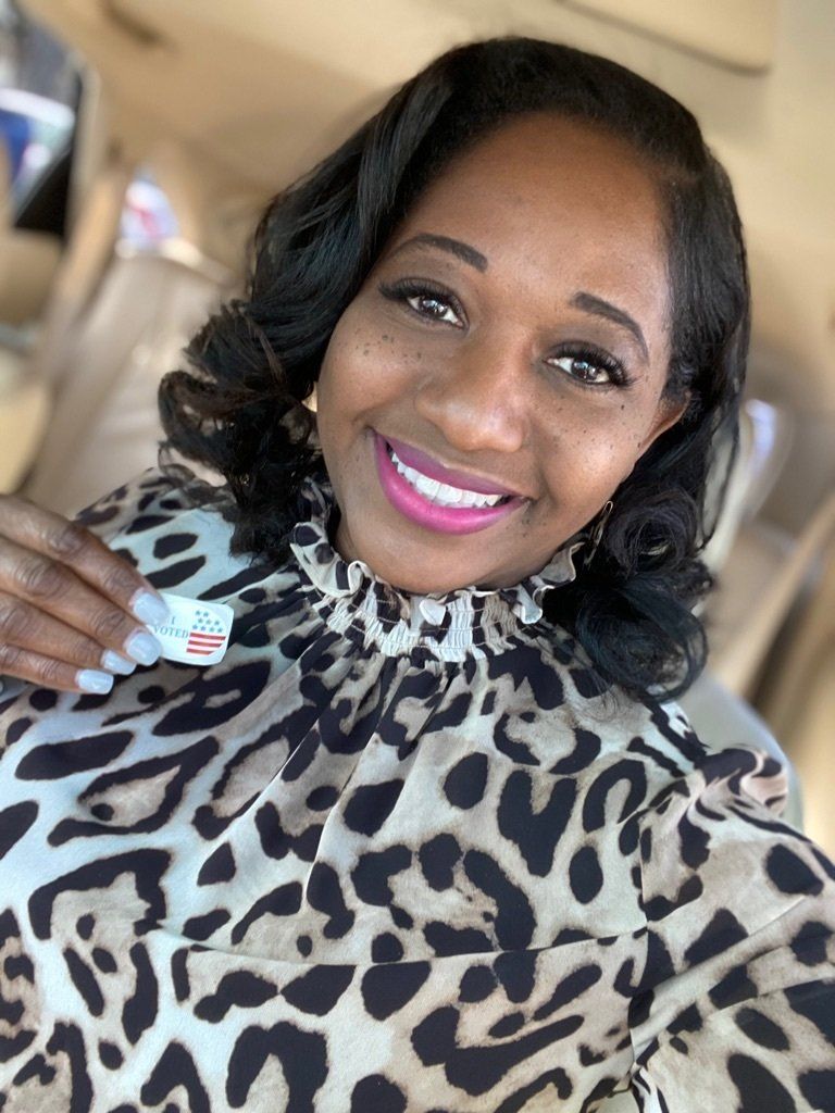 Woman in leopard print shirt smiles, holding a sticker. Indoor setting, soft lighting.