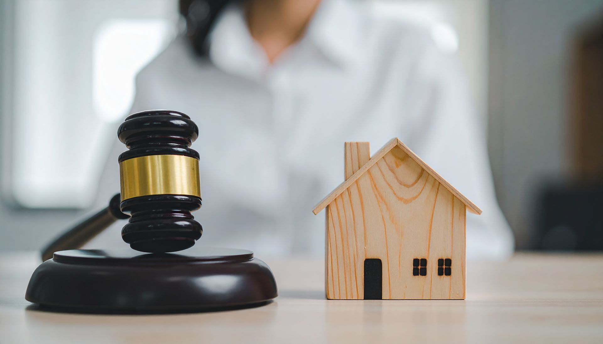 Judge gavel and miniature house on desk.