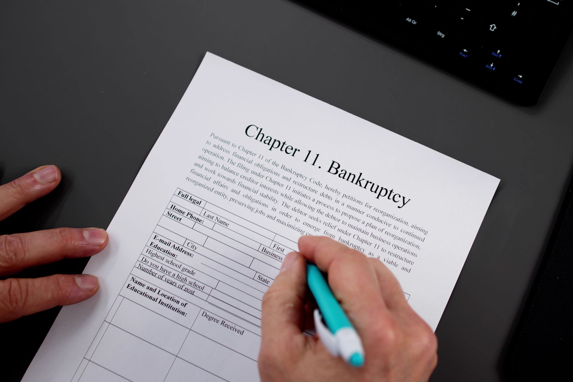 Person writing on Chapter 11 bankruptcy document with a blue pen. Person writing on Chapter 11 bankruptcy document with a blue pen.