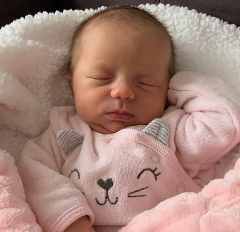 Sleeping newborn baby dressed in a pink onesie