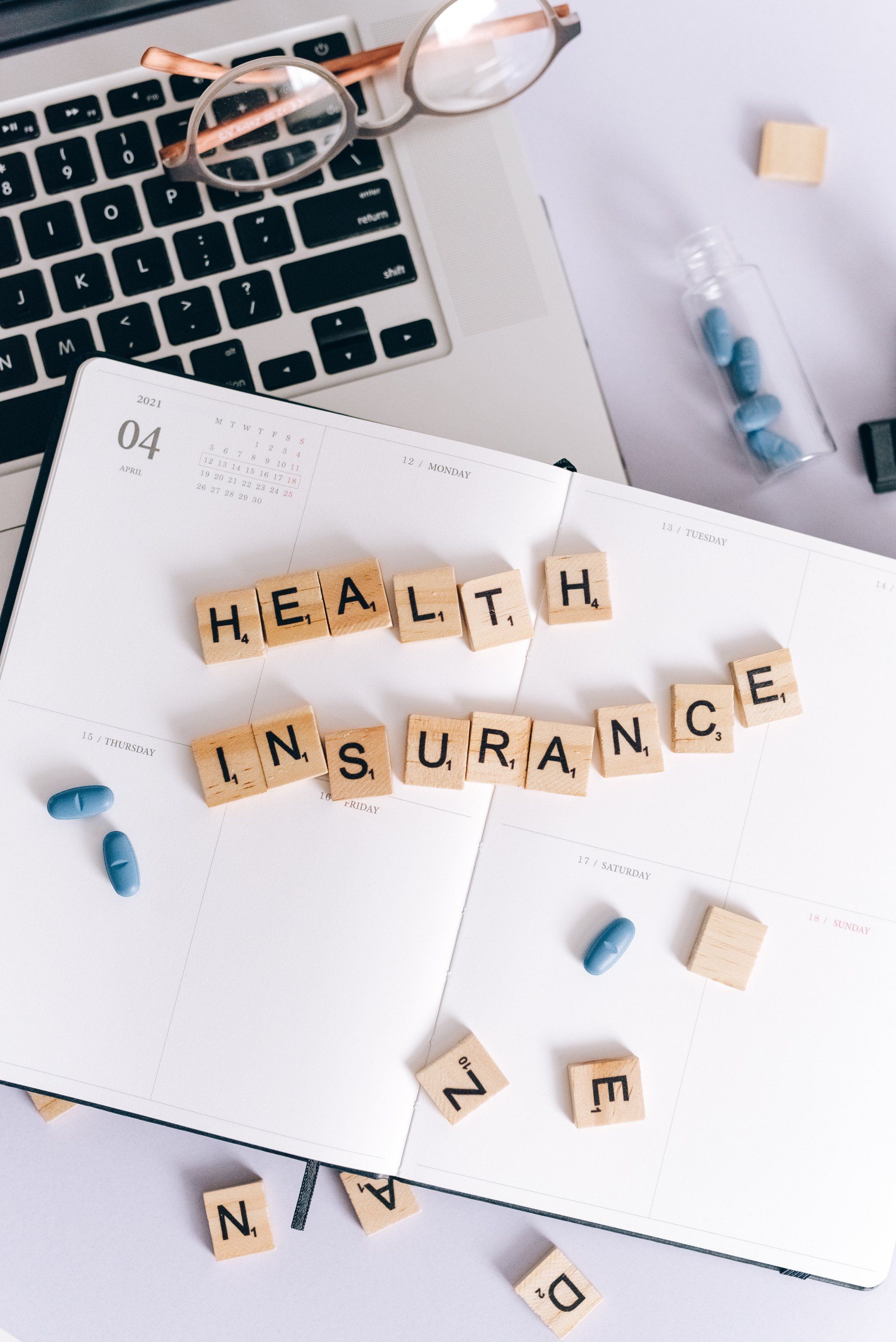 Scrabble letters laid out on a book spelling out the words "health insurance"