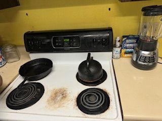Kitchen stovetop with black kettle and pan on burners, blender on counter.