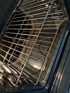 An oven interior with a wire rack. The interior is dark with some visible debris.