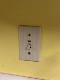 White light switch on a yellow wall, in the 