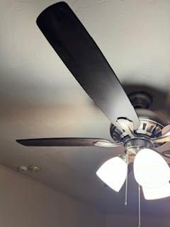 Ceiling fan with dark blades, three lights, mounted on a white ceiling.