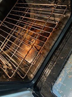 Dirty oven interior with rack, heavy grease buildup on the bottom and sides.