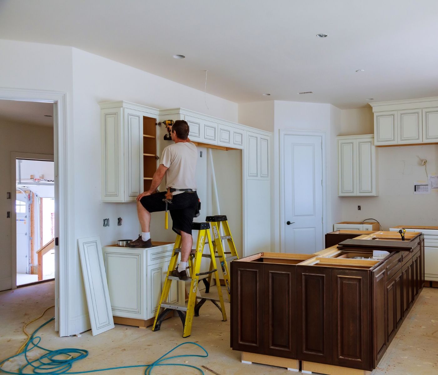 A man is standing on a ladder in a kitchen.