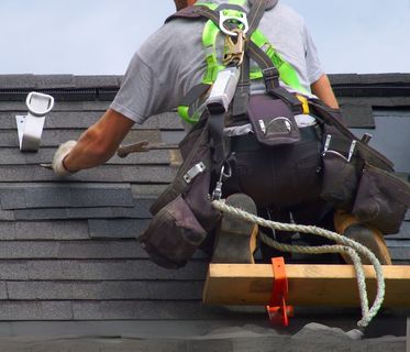 A man wearing a safety harness is working on a roof