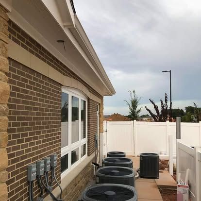 Brick building with air conditioning units, white fence, and cloudy sky.