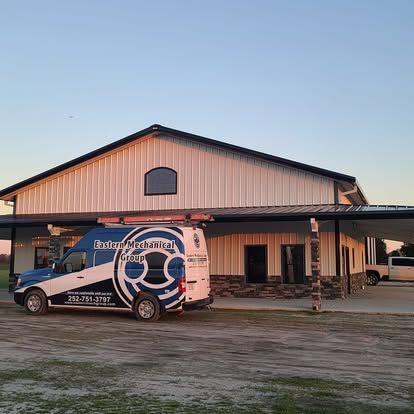 Van parked in front of a metal building. The van has a company logo on the side.