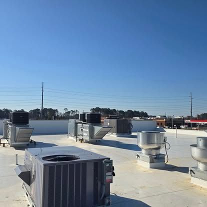 Rooftop with HVAC units under a clear blue sky, power lines in background, and commercial buildings.