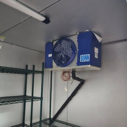 Refrigerator interior with shelving and a Bohn cooling unit mounted on the ceiling.
